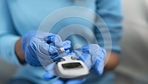 Young nurse checking glycemia test for diabetes while wearing surgical gloves - Healthcare concept photo