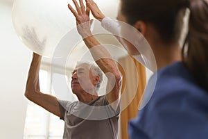 Young nurse doing exercise with senior man.