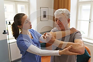 Young nurse doing exercise with senior man.