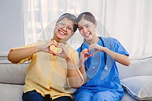 young nurse and an elderly person give a thumbs up showing the good health from the treatment of the elderly