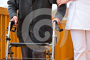 Young nurse and female senior with walking frame