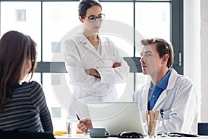 Young nurse listening to an experienced physician while consulting a patient