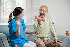 Young nurse physiotherapist support senior old man to lifting dumbell at home