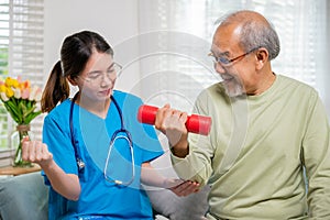 Young nurse physiotherapist support senior old man to lifting dumbell at home