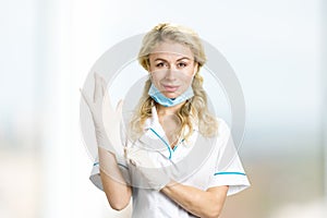 Young nurse putting on gloves.