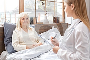 Nurse taking care of senior woman writing prescription retirement concept