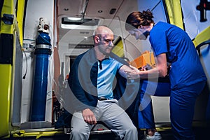 A young nurse in a uniform giving an injection to a patient in an ambulance car