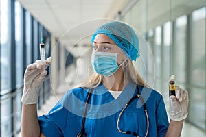 young nurse in uniform and mask holding a syringe in his hands on the corridor