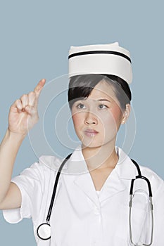 Young nurse using transparent screen over light blue background