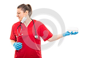 Young nurse wearing red scrub holding bad smelling lunch box