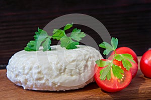 Young oak cheese cutting Board with tomatoes and parsley. Mozarella for pizzas and salads.