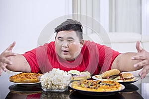 Young obese man looks tempted to eat lots of food