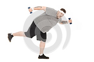 Young obese man running with dumbbells and looking at camera