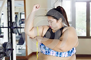 Young obese woman measuring her upper arm