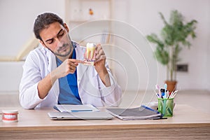 Young male odontologist working in the clinic photo