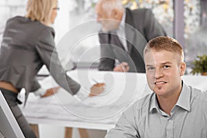 Young office worker with colleagues in background