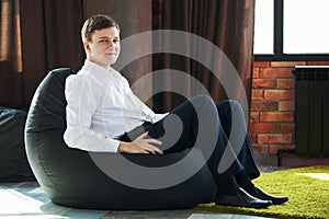 Young office worker sitting on a soft chair and smiling.