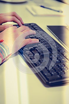 Young office worker typing on pc keyboard responses to emails.