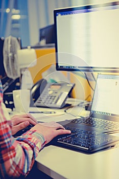 Young office worker typing on pc keyboard responses to emails.