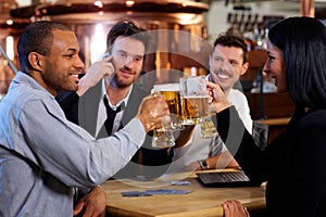 Young office workers toasting with beer at pub