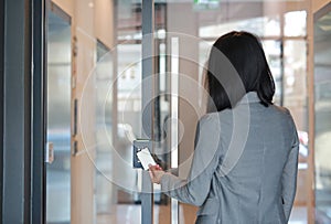 Young officer woman holding a key card to lock and unlock door for access entry. Door access control. Back view