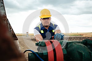 Oil worker is turning valve on the oil pipeline. Oil and Gas Industry.