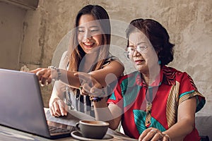 Young and old asian women are using laptop together