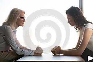 Young and old businesswomen sitting opposite, generations conflict at work