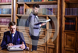 Young oldfashioned writer with typewriter in library with bearded friend