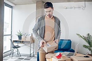 Young online shop worker preparing goods for transportation