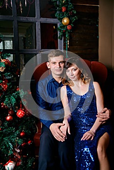 Young ordinary family of two. Young husband and wife near christmas tree. Happy young hetero couple decorate christmas tree at