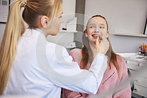 Young orthodontist checking patient in dentist`s office