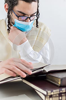 Young Orthodox Jew wearing a protective mask and studying religious texts