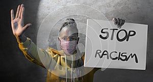 Young outraged and hipster African American woman holding protest banner demanding stop racism and racial discrimination