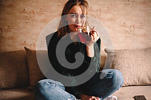 Young woman drinking tea while sitting on sofa at home