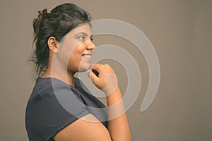 Young overweight beautiful Asian woman against gray background