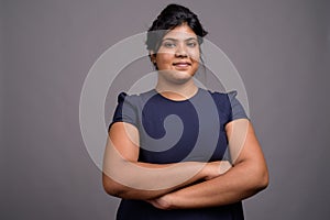 Young overweight beautiful Indian woman against gray background