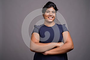 Young overweight beautiful Indian woman against gray background
