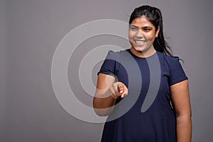 Young overweight beautiful Indian woman against gray background