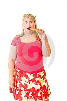 Young overweight blond woman eating raw carrot