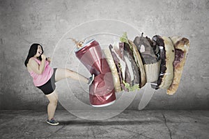 Young overweight woman kicking unhealthy foods