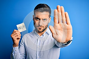 Young overworked business man asking for help holding paper over blue background with open hand doing stop sign with serious and
