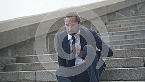 Young overworked businessman walking down stairs and having heart attack. Camera approaches to ill Caucasian man with