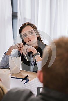 young overworked manageress sitting at workplace with box of chinese food photo