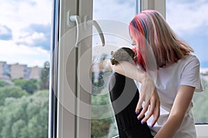 Young owner with pet and degu squirrel. Teenage girl looking out the window