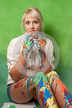 Young painter covered with paint on a bright green background