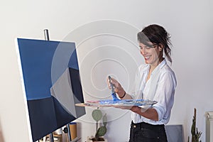 A young painter mixing the paint on the palette in studio