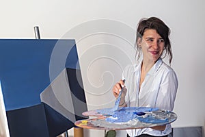 A young painter mixing the paint on the palette in studio