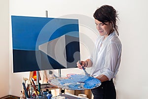 A young painter mixing the paint on the palette in studio