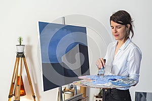 A young painter mixing the paint on the palette in studio